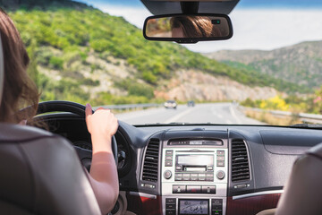 The girl is driving on the road on Tenerife, Canary Islands. View from the back seat of the car on...