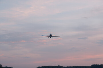 Fototapeta na wymiar Small single engine airplane flying against sunset sky.