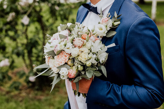 the groom holds the bride's bouquet, the wedding bouquet on the background of the jacket, the wedding day