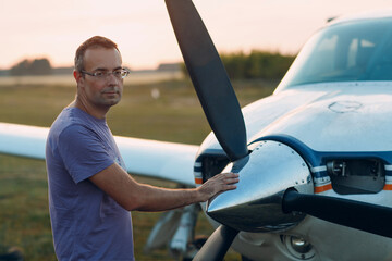 Pilot man standing next to a small private airplane