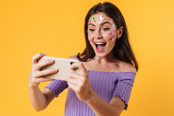 Image of excited woman playing video game on cellphone