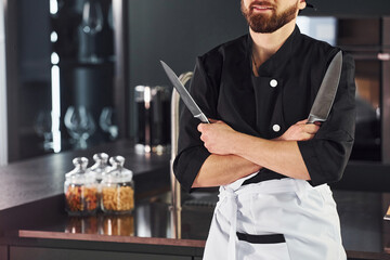 Professional young chef cook in uniform standing and preparing for the work on kitchen