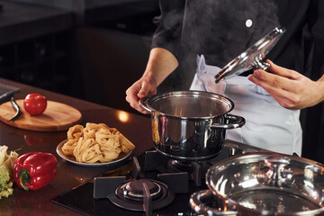 Using equipment. Professional young chef cook in uniform working on the kitchen with vegetables