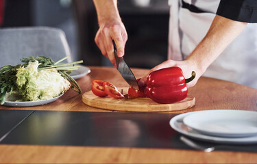With vegetables. Professional young chef cook in uniform working on the kitchen
