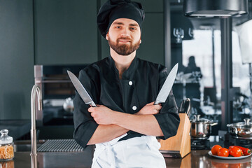 Portrait of professional young chef cook in uniform that posing for camera on the kitchen