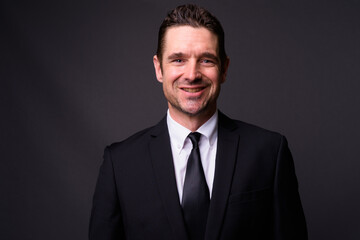 Portrait of happy handsome bearded businessman in suit