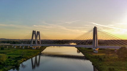 Monumental, lighted, new modern double cable-stayed bridge over Vistula River in Krakow, Poland during sunset. Concrete and steel industrial construction from supports S7 highway. Drone photography.