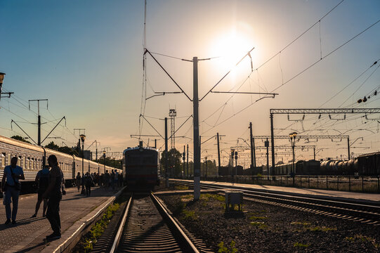 an old electric train drives up to the station platform along the rails at sunset
