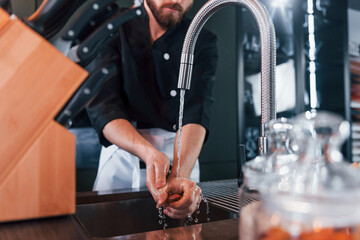 Professional young chef cook in uniform washing hands on the kitchen