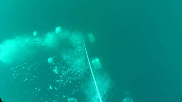Divers gradually descend in depth along the trigger halyard.