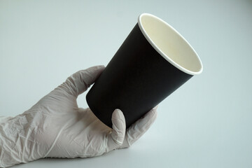 barista with gloves holding a black disposable coffee cup