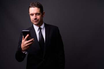 Portrait of handsome bearded businessman in suit using phone