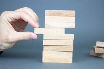 Business planning, risk and strategy, businessman and gambling engineer taking out a wooden block on their towers.