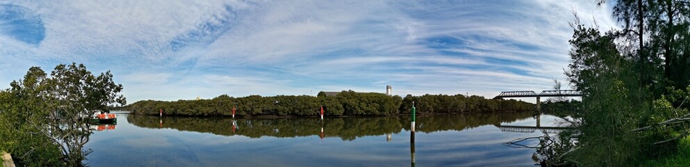 Beautiful panoramic view of a river with reflections of trees, deep blue sky and rainbow look-alike clouds on water, Parramatta river, Rydalmere, Sydney, New South Wales, Australia
