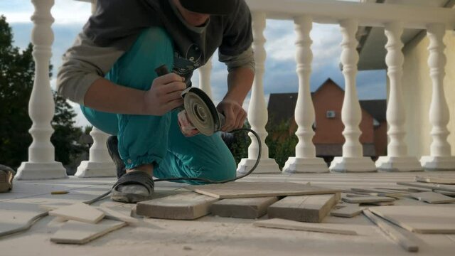 Contractor Worker Cuts with Angle Grinder Ceramic Tiles on Balcony Floor. Slow motion
