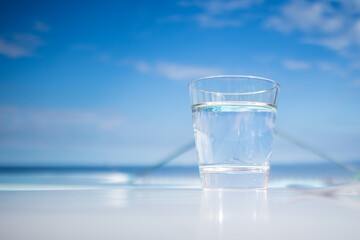 Glass of water standing near swimming pool in hot summer