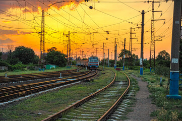 Fototapeta na wymiar old Electric multiple unit train on railways at the entrance to the station at sunrise in Mariupol, Ukraine