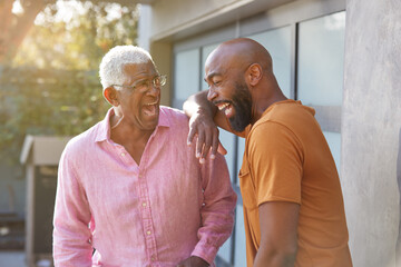 Senior Father Talking And Laughing With Adult Son In Garden At Home