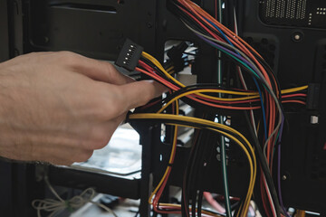 Young man repairs a computer system unit, changes parts, video card and hard drive, sets new components. Computer Repair Wizard.