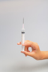 Hand holding syringe on gray background
