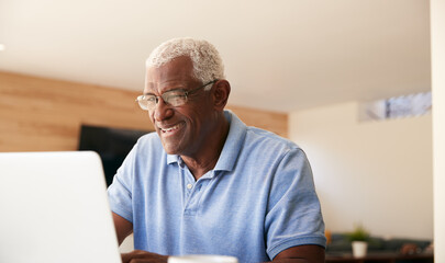 Senior African American Man Using Laptop To Check Finances At Home - Powered by Adobe