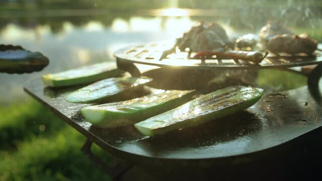 Pieces of steaming grilled zucchini near chili peppers. a man turns over