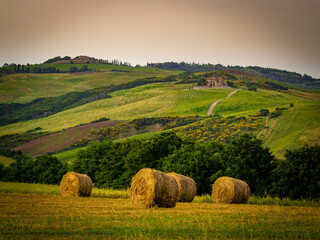 Farmland with hay rolls and farmhouses in Tuscany Italy