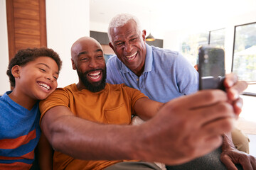 Multi-Generation Male African American Family On Sofa At Home Posing For Selfie On Mobile Phone