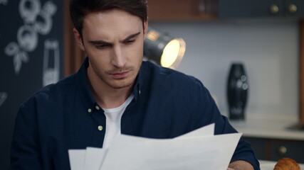 Focused business man looking on diagrams at home office. Man reading documents