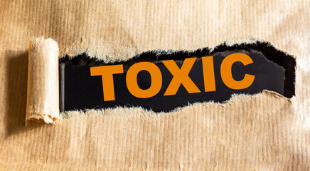 Toxic the word is written on torn brown paper