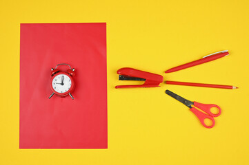 Alarm clock and stationery in red and yellow tones.