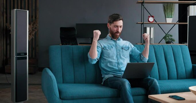 Excited young Man Winner holding using Laptop, working Home. Male feels overjoyed with Success while working distantly, happy caucasian Man euphoric screaming, celebrats good news victory Success.