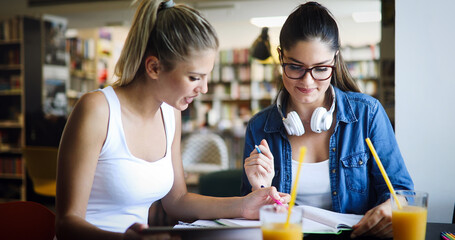 Happy young university students friends studying with books at university