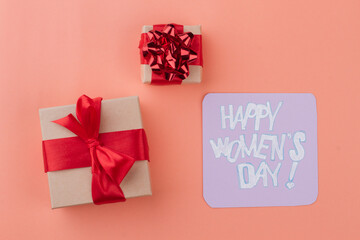 Happy women's day wish and gift boxes with red ribbon. Top view from above. Isolated on orange background.