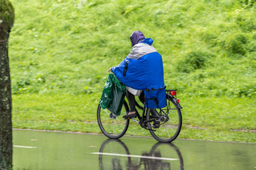 Obraz premium Radfahrer mit Regenpelarine am Radweg