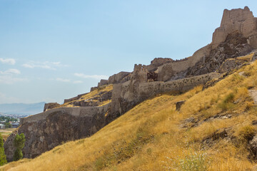 Panoramic view of the Van Castle in Van city, Eastern Turkey. The Old Fortress of Urartu located on the rocks. Massive clay and stone walls on golden hills in the sun