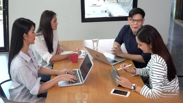 group of young asian business people team meeting at coworking space in modern office discussing business plan and  brainstorm . entrepreneurs man Present Strategy to partner woman