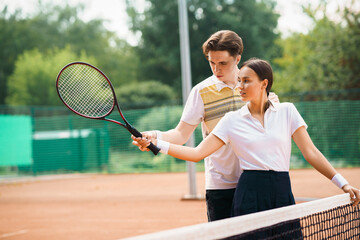 Coach teaches a girl to play tennis