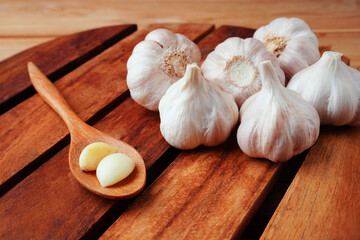 Garlic bulb and garlic clove in  wooden spoon on the table.