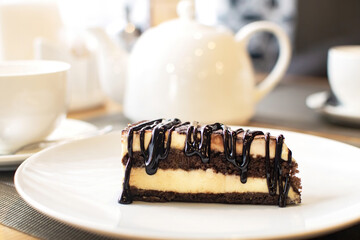 Slice of tasty chocolate tiramisu on white plate on table in cafe. Traditional Italian biscuit dessert or cake.