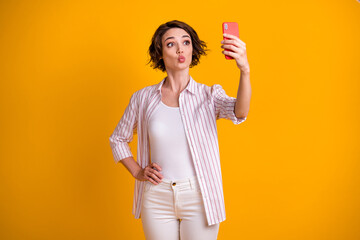 Photo of romantic dreamy girl make selfie on her smartphone send air kiss to her blog followers wear white trousers isolated over bright shine color background