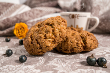 Homemade oatmeal cookies and a cup of coffee on a silver cloth.