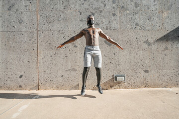 Athletic black man is training in urban area while wearing a mask.