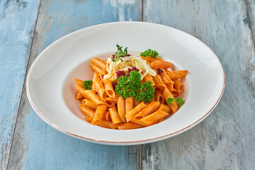 Penne pasta in tomato sauce with  cheese, tomatoes decorated with parsley