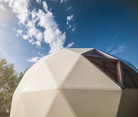 White geodesic dome tent for glamping in summer day  with blue sky
