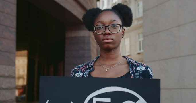 Crop view of female african american activist holding placard with no 5g sign. Student girl doing single protest against new technology and compatible antenna deployment at city street