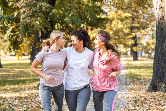 Group of female friends jogging at the city park.Relaxing after running and making fun.Autumn season.