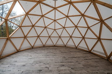 Interior of large geodesic wooden dome tent with window and view to forest. Empty interior glamping tent.