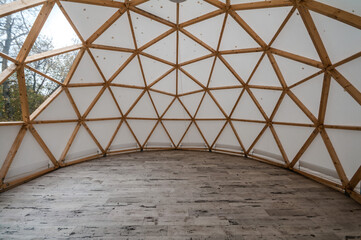 Interior of large geodesic wooden dome tent with window and view to forest. Empty interior glamping...