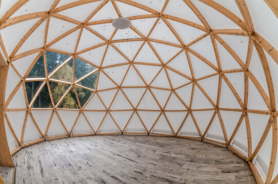 Interior of large geodesic wooden dome tent with window and view to forest. Empty interior glamping tent.
